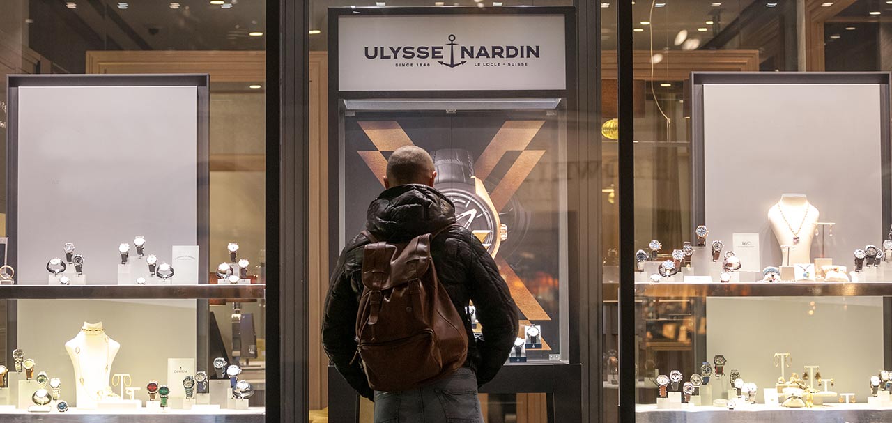 Man with backpack shopping outside of a Ulysse Nardin watch store