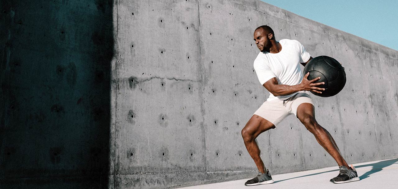 Man exercising outside with weighted medicine ball