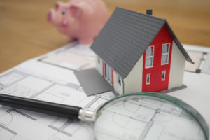 piggybank, house and magnifying glass showing inflation